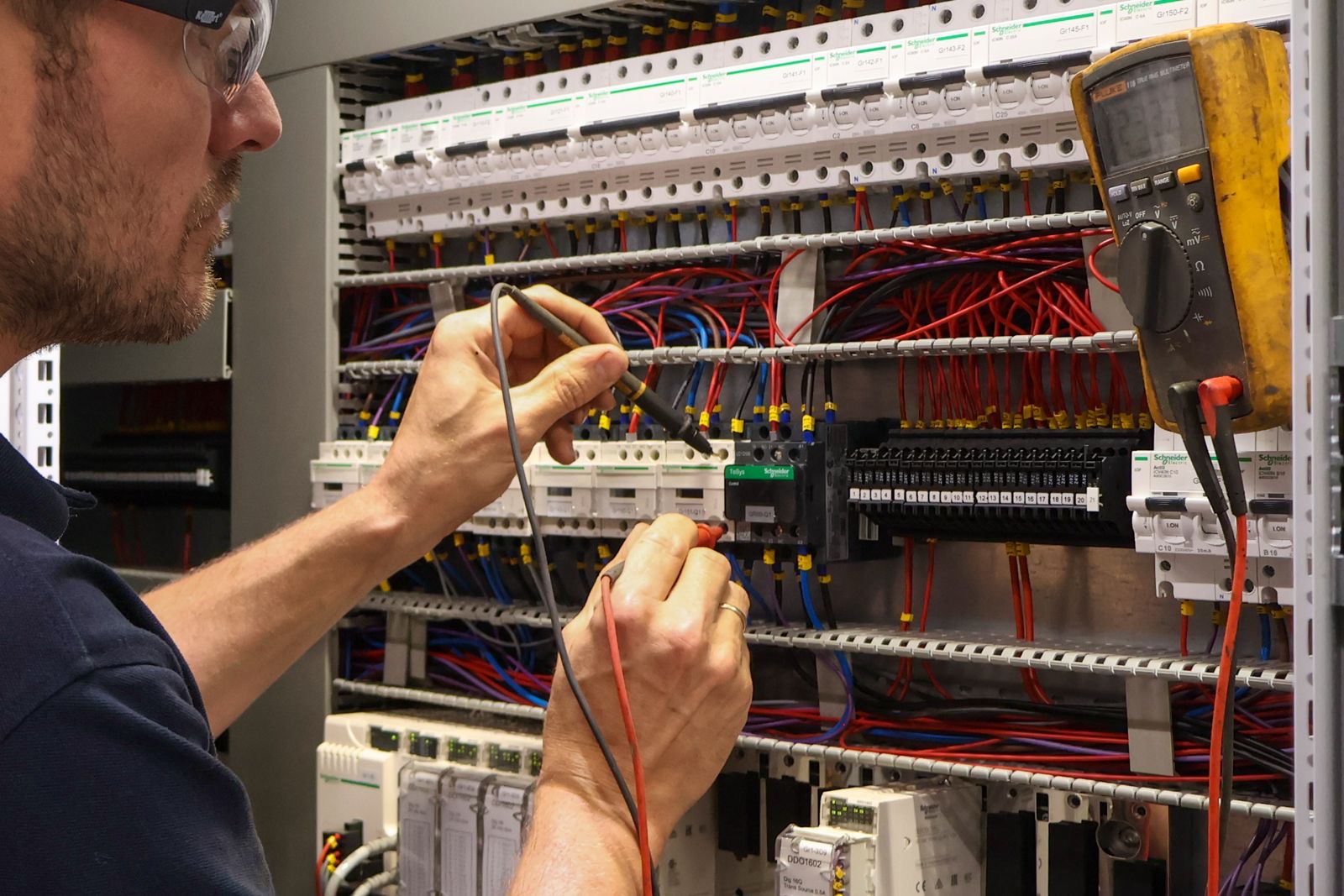 Technicus meet componenten in een industriële schakelkast door